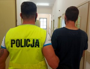 policjant prowadzi osobę zatrzymaną