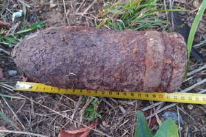 Pocisk leżący w trawie i przyłożona do niego miarka