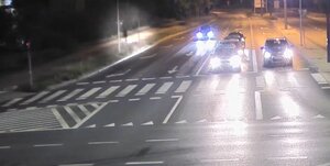 Zrzut ekranu z zapisu monitoringu. Po prawej kierujący hulajnogą podczas jazdy ścieżką rowerową wzdłuż ulicy.