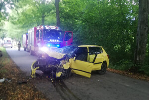 Miejsce zdarzenia drogowego. Rozbity samochód na drodze i wóz strażacki za nim