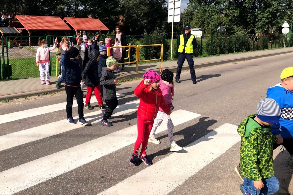 Dzieci przechodzące przez przejście pod nadzorem policjanta