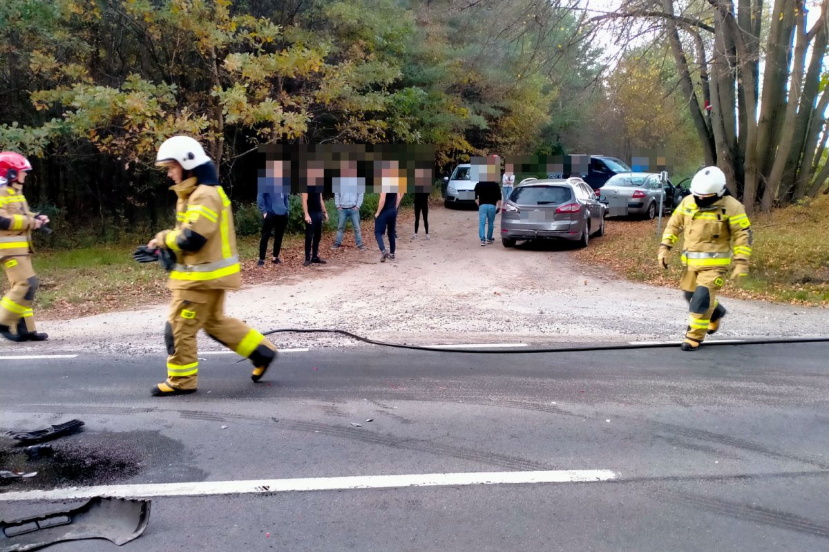 Rozbite samochody i służby na miejscu zdarzenia. Uszkodzony samochód i strażacy na drodze.