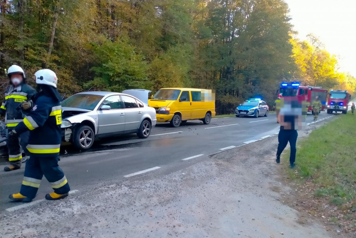 Rozbite samochody i służby na miejscu zdarzenia. Uszkodzony samochód i strażacy na drodze.