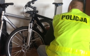 Policjant kucający obok roweru