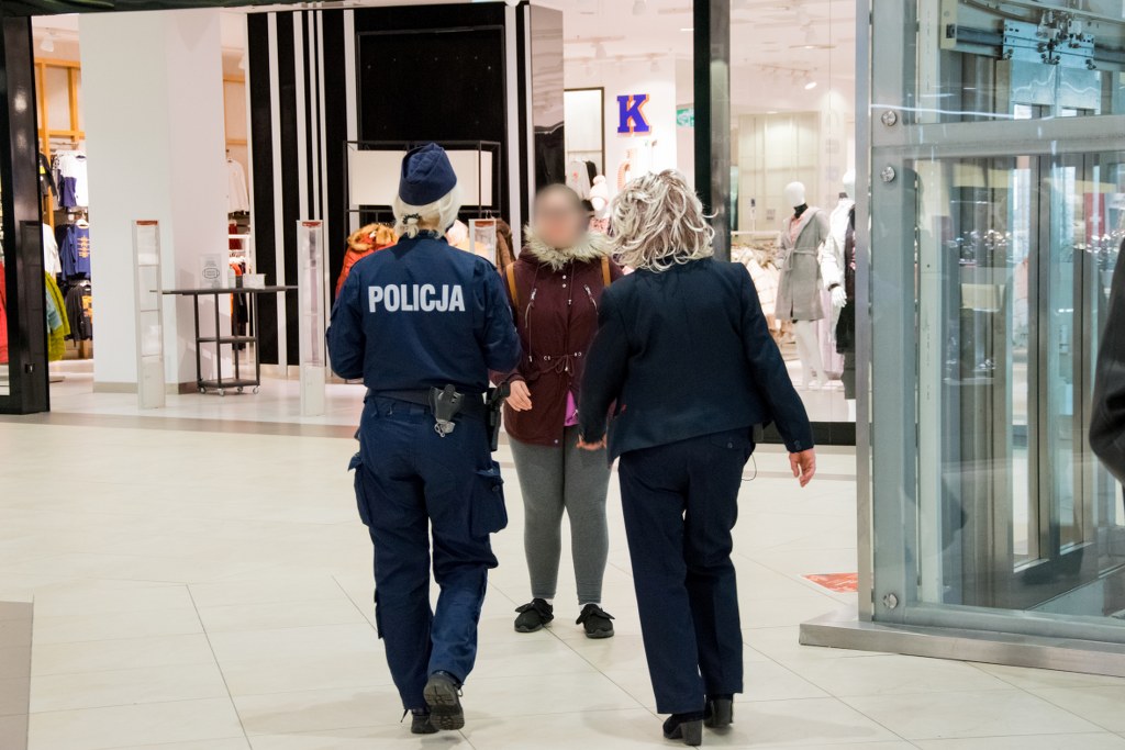 Policjanci w trakcie służby wręczają maseczki klientom centrum handlowego