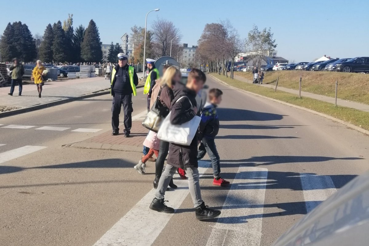 Policjanci podczas służby w Działdowie. Policjant nadzorujący ruch na przejściu dla pieszych i piesi przechodzący przez nie