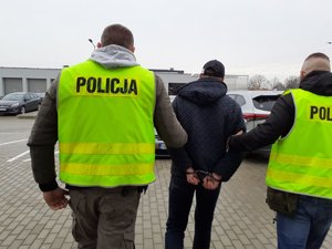 policjanci prowadzą osobę zatrzymaną