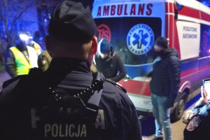 Funkcjonariusze na miejscu kontroli stojący obok zatrzymanej karetki