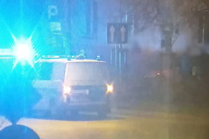 Radiowóz z włączonymi sygnałami świetlnymi stojący w nocy na ulicy