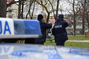 Dach radiowozu a w tle policjanci w parku