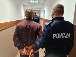 policjant prowadzi osobę zatrzymaną