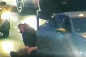 Policjant udzielający pomocy nieprzytomnemu mężczyźnie leżącemu na ulicy obok samochodu