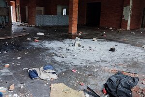 Miejsce w pustostanie, gdzie płonęło toksyczne ognisko. Porozrzucane śmieci oraz pozostałości ogniska i popiół na środku posadzki w pomieszczeniu.