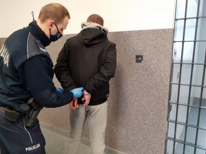 Policjant zakłada kajdanki na ręce zatrzymanego