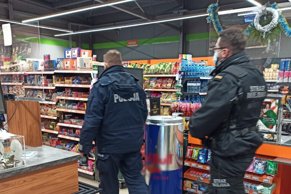 Policjant i strażnik miejski w sklepie podczas kontroli