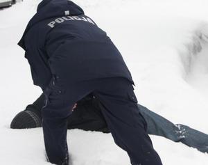 Policjant interweniujący wobec osoby leżącej na sniegu