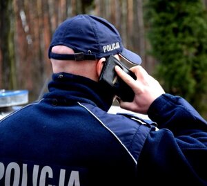 umundurowany policjant trzyma w przy uchu telefon komórkowy