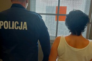 Zatrzymana kobieta prowadzona przez policjanta