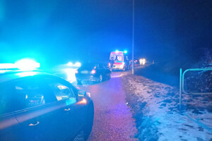 Miejsce przekazania rodzącej pod opiekę medyków. Na drodze stoją radiowóz policyjny, samochód cywilny i karetka pogotowia