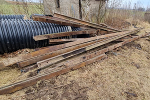 Skradzione elementy trakcji i rury odzyskane przez policjantów. Przedmioty leżą na trawie na posesji