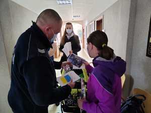 Policjant w trakcie rozmowy rozdaje ulotki i odblaski