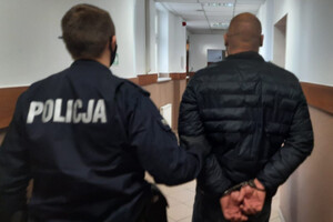 Zatrzymany mężczyzna prowadzony przez policjanta