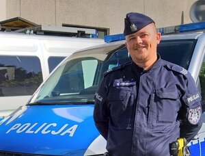 policjant umundurowany stojący przy radiowozie