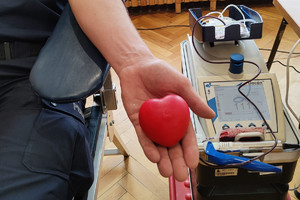Policjant w trakcie poboru krwi siedzący w fotelu i trzymający przedmiot w kształcie serca