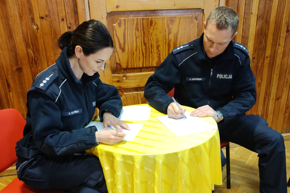 Policjanci wypełniający dokumenty, siedzący przy stoliku
