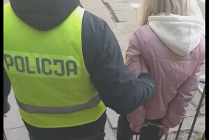 Zatrzymana kobieta prowadzona przez policjanta