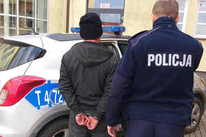 Zatrzymany mężczyzna prowadzony przez policjanta do radiowozu