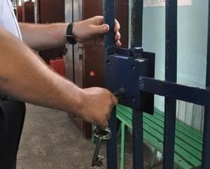 policjant zamyka kratę celi
