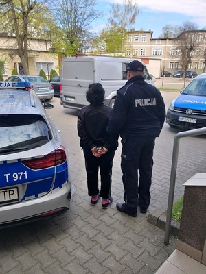 Policjant prowadzi osobę zatrzymaną