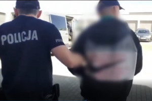 Zatrzymany mężczyzna prowadzony przez policjanta do radiowozu