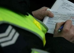 policjant w radiowozie wypisuje mandat