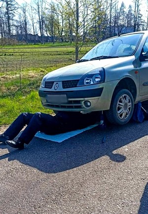 policjant naprawia uszkodzone auto