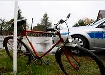 Rower stojący na trawniku a w tle radiowóz