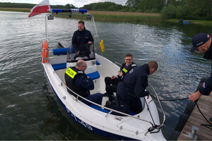 łódź na wodzie oraz cztery osoby na pokładzie