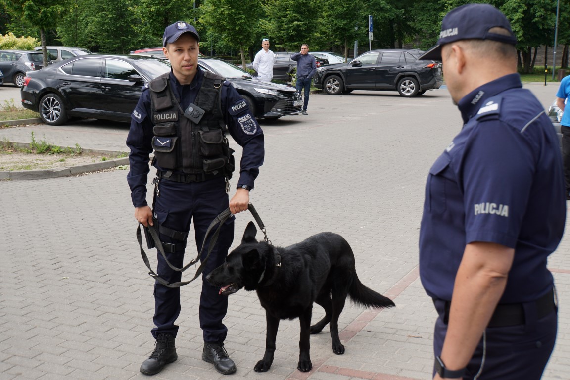Policjant przewodnik psa służbowego z psem oraz umundurowany policjant