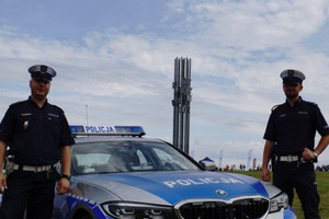 Policjanci obok radiowozu na tle pomnika Bitwy pod Grunwaldem