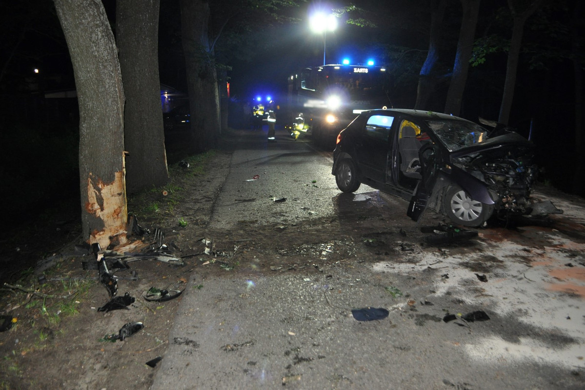 Miejsce zdarzenia drogowego w powiecie giżyckim. Rozbity samochód stojący na drodze obok drzewa w które uderzył