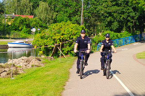 Dwoje policjantów jadących rowerami po ścieżce rowerowej