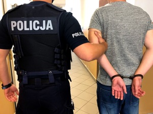 Policjant prowadzi osobę zatrzymaną
