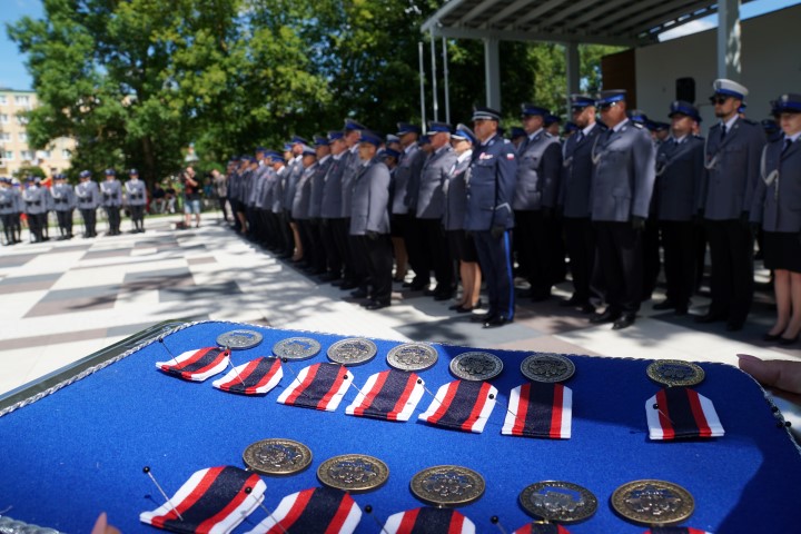 Medale dla odznaczonych a w tle stojący policjanci