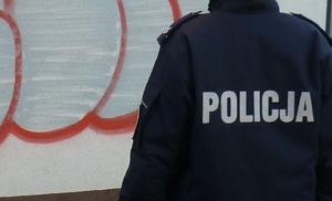 Policjant stojący na tle ściany ze śladem farby w sprayu