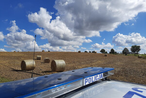 Dach radiowozu na tle pola z balotami