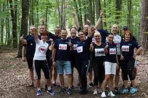 Uczestnicy biegu biegnący leśną ścieżką