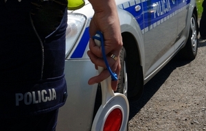 policjant pr4zy radiowozie z tarczą do zatrzymywania