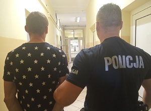 Policjant prowadzi osobę zatrzymaną