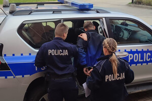 Zatrzymany mężczyzna prowadzony przez policjantów do radiowozu